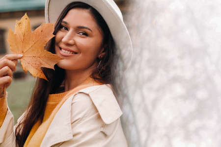a girl in a white coat and hat smiles in an autumn Park.Portrait of a woman in Golden autumn.