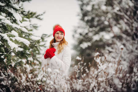 Portrait of a woman in white clothes and a red hat in a cold winter forest. Girl in a snow-covered winter forestの写真素材