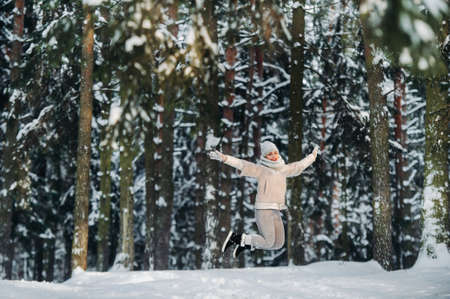 a woman in gray clothes jumps emotionally in a winter forest.Girl in the new year's snow-covered forestの写真素材