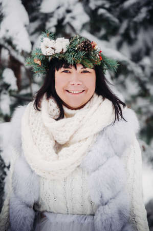 PPortrait of a woman in white clothes in a cold winter forest. Girl with a wreath on her head in a snow-covered winter forest.の写真素材