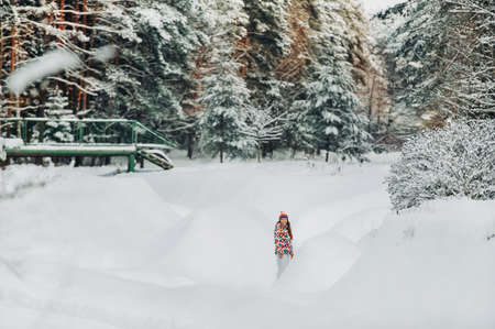 Portrait of a woman in white clothes in a cold winter forest. A girl with a white hat on her head in a snow-covered winter forest.の写真素材