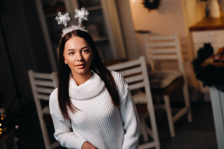 Girl at Christmas with horns in the home interior.A woman on New year's eve in a white sweater.の写真素材