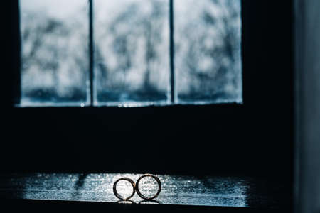 two gold wedding rings on the windowsill in the sunlight.の写真素材