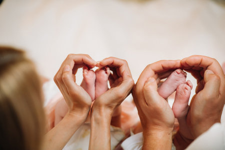 the newborn's legs are held in the hands of the mother and father in the form of a heart. children's feet in the hands of parents.の写真素材