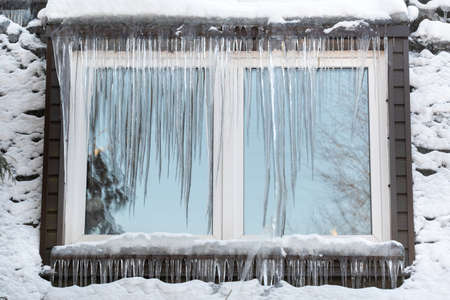 Icicles on the window of the house on a frosty day..の写真素材