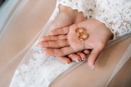 Close-up of two gold wedding rings in the palm of your hand.の写真素材