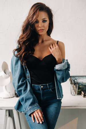 a brunette with long hair poses in the interior sitting on a tableの写真素材