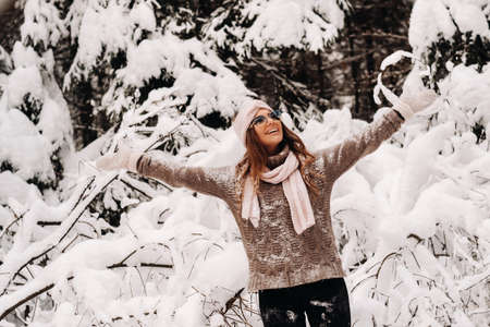 A girl in a sweater and glasses in winter in a snow-covered forestの写真素材
