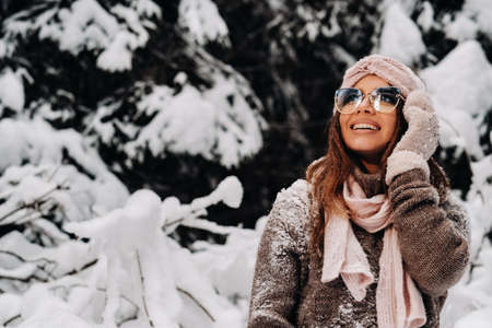 A girl in a sweater and glasses in winter in a snow-covered forestの写真素材