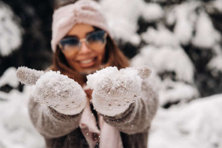 A girl in a sweater and glasses in winter in a snow-covered forestの写真素材