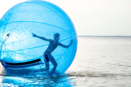 A girl in an inflatable attraction in the form of a ball on the seaの写真素材