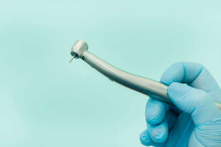 a dentist wearing gloves in the dental office holds a tool before workingの写真素材