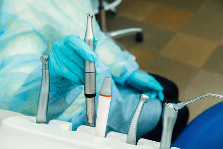 a dentist wearing gloves in the dental office holds a tool before working.の写真素材