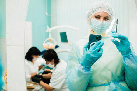 the dentist in a protective mask stands next to the patient and takes a photo after work.の写真素材