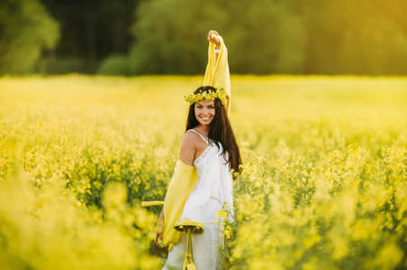 a woman enjoys a bike ride in a field full of bright yellow rapeseed.の写真素材