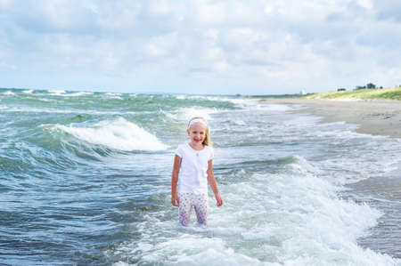 Happy Little girl in clothes on the Baltic Sea beach on the Curonian spit in Lithuania.の写真素材