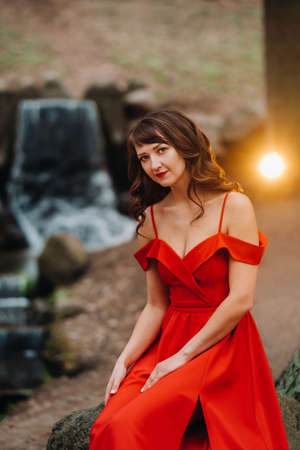 Spring Portrait of a laughing girl in a long red dress with long hair walking in the Park in the woodsの写真素材