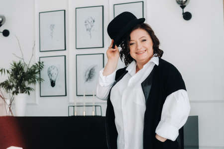 A businesswoman in a white shirt and trousers is standing with a hat in her hands standing in the office.の写真素材