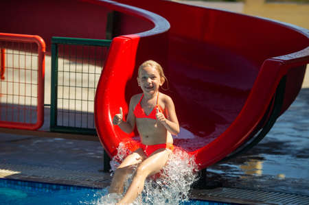 A little girl in a pink swimsuit slides down a water slide in a water park during the summer holidays.Greece.の写真素材