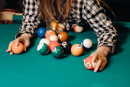 A girl in a hat in a billiard club with balls in her hands.Playing pool.