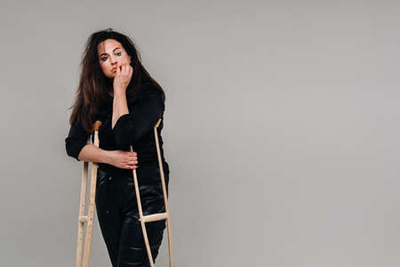 A battered woman in black clothes with casters in her hands on a gray background.の写真素材