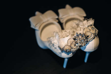 white wedding shoes and garter belt on black background.の写真素材