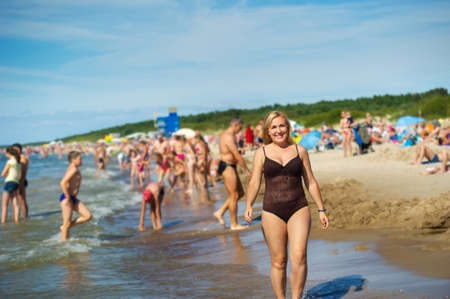 Front view of a beautiful girl walking along the beach along the Baltic Sea in a brown swimsuit. Palanga, Lithuaniaの写真素材