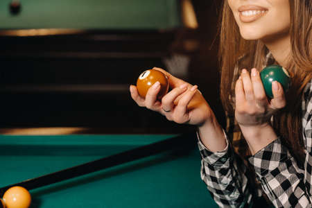 A girl in a hat in a billiard club with balls in her hands.Playing poolの写真素材