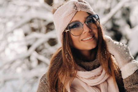 A girl in a sweater and glasses in winter in a snow-covered forest.の写真素材
