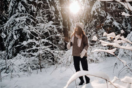 A girl in a sweater and glasses in winter in a snow-covered forest.の写真素材