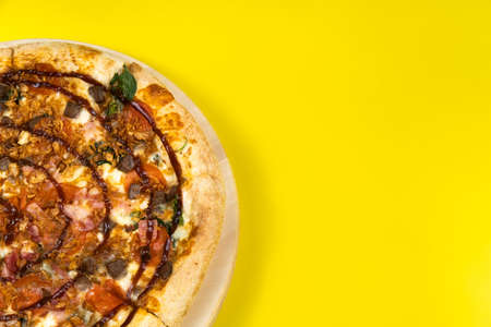 Delicious large pizza with bacon and spinach on a yellow backgroundの写真素材