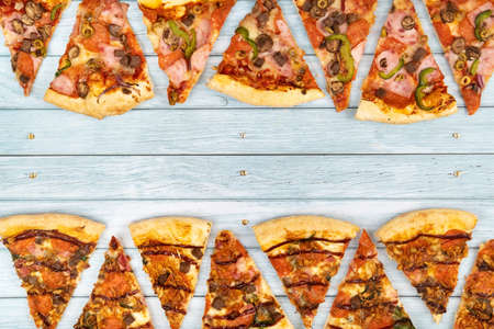 Lots of delicious triangular pizza slices on a blue wooden background