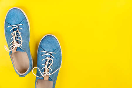 Blue shoes stand on an isolated yellow background.の写真素材