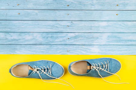 The blue shoes stand on an isolated mixed blue and yellow background.の写真素材