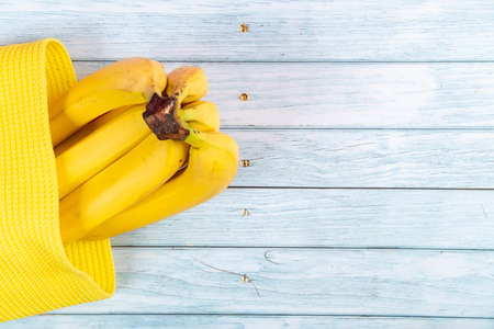 yellow bananas lying in a yellow bag on a blue wooden background.の写真素材