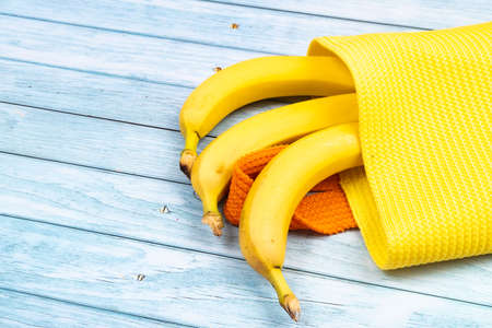 yellow bananas lying in a yellow bag on a blue wooden background.の写真素材