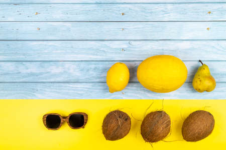 An assortment of yellow fruits and glasses lie on a blue wooden background and a yellow background.の写真素材