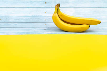 Yellow bananas lie on a blue wooden background and a yellow background.の写真素材