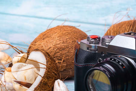 camera, coconuts and shells on a blue wooden background.Marine theme.