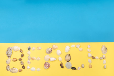 The inscription of the word beach is made of shells on a yellow-blue background.Travel concept.の写真素材
