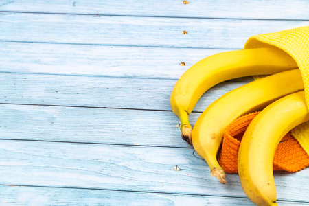 yellow bananas lying in a yellow bag on a blue wooden backgroundの写真素材