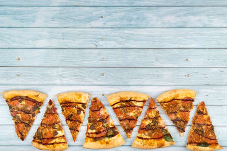 Lots of delicious triangular pizza slices on a blue wooden background.の写真素材