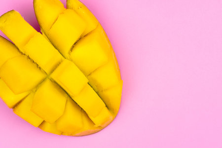 Fresh ripe mango on a pink background. Half a sliced mango on a pink background.の写真素材