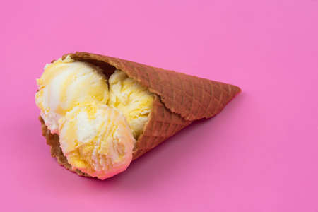 Fruit-scented ice cream balls in a waffle cone on a pink background