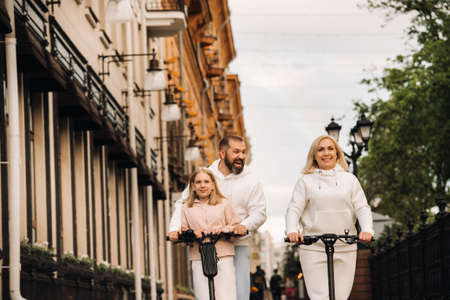 A family in white clothes rides electric scooters in the city.Outdoor activitiesの写真素材