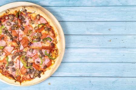 Delicious large pizza with veal and mushrooms on a blue wooden background.の写真素材