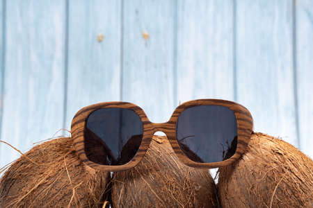 three whole coconuts and wooden glasses on a blue wooden background.
