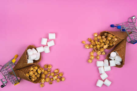 two shopping baskets with ice cream cones with sweets on a pink background.の写真素材