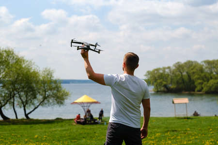 A man with a quadrocopter in his hands, raised to the sky in nature.の写真素材