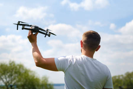 A man with a quadrocopter in his hands, raised to the sky in nature.の写真素材